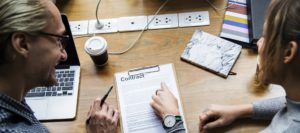 Woman pointing at contract while man smiles.